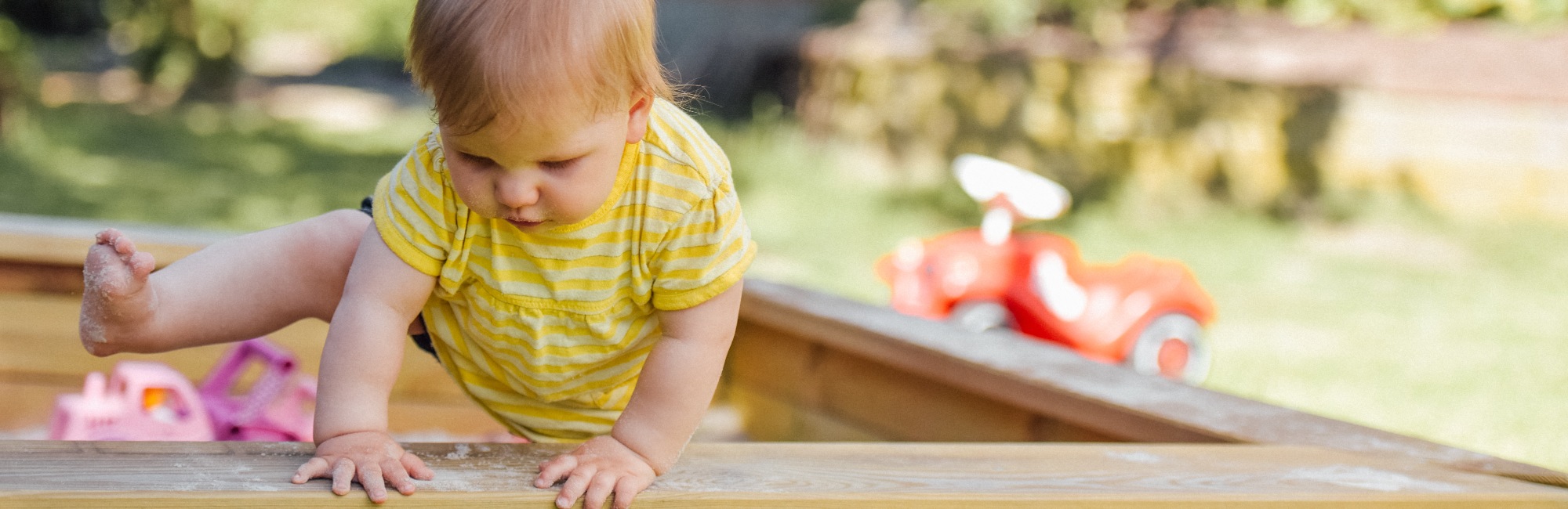 toddler climbing out of sand pit