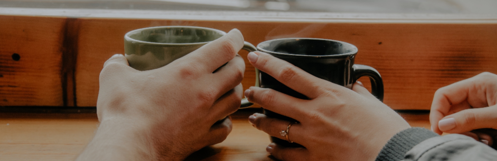two different hands holding mugs