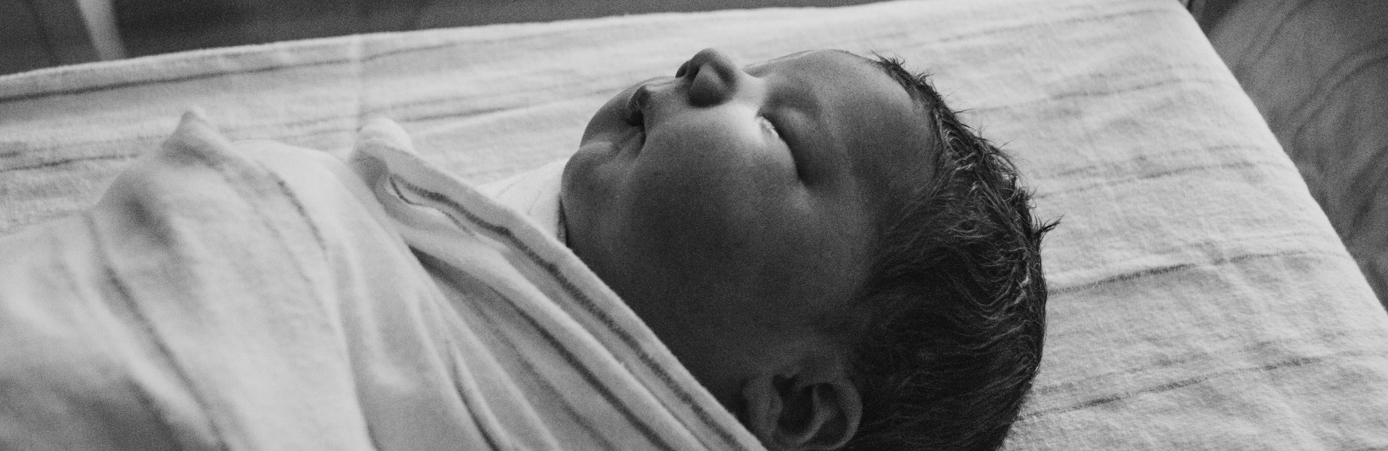 a swaddle wrapped baby sleeping on its back