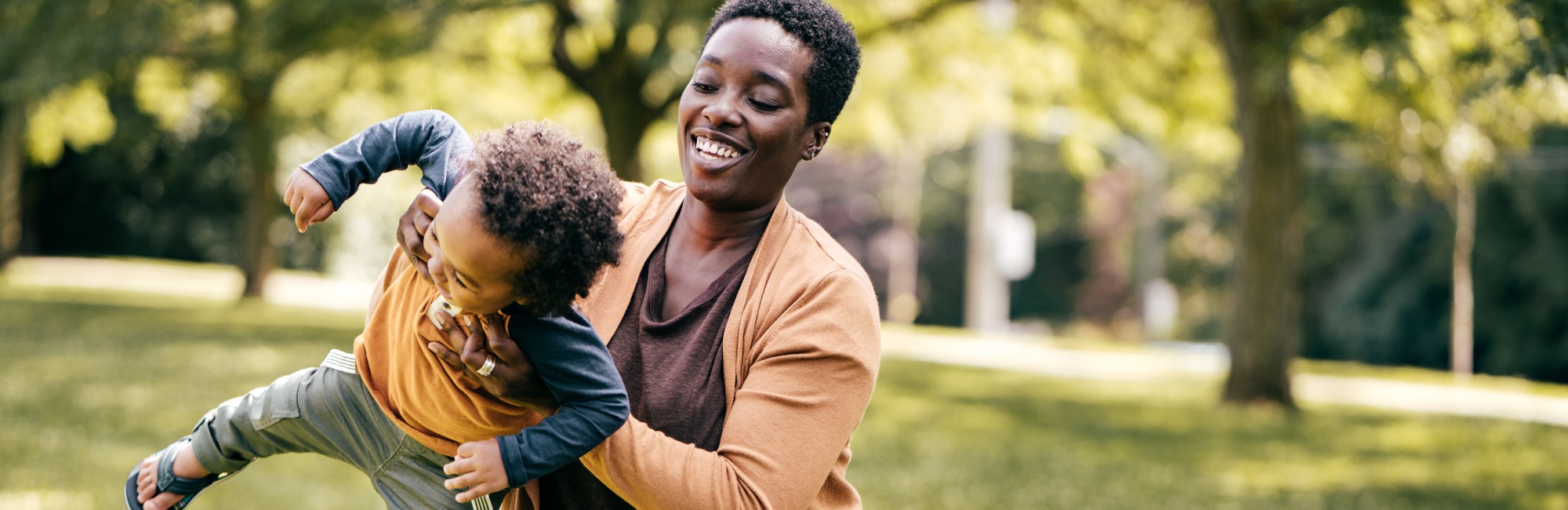 mother plays joyfully in a park with toddler