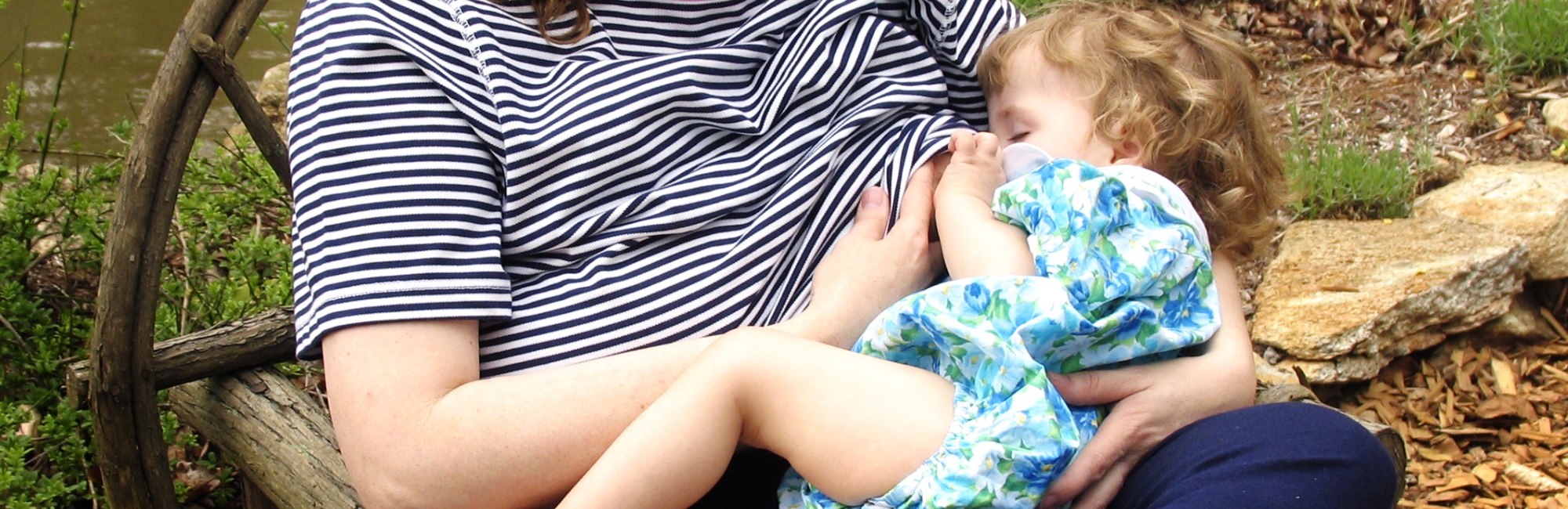 toddler breastfeeding outside on park bench