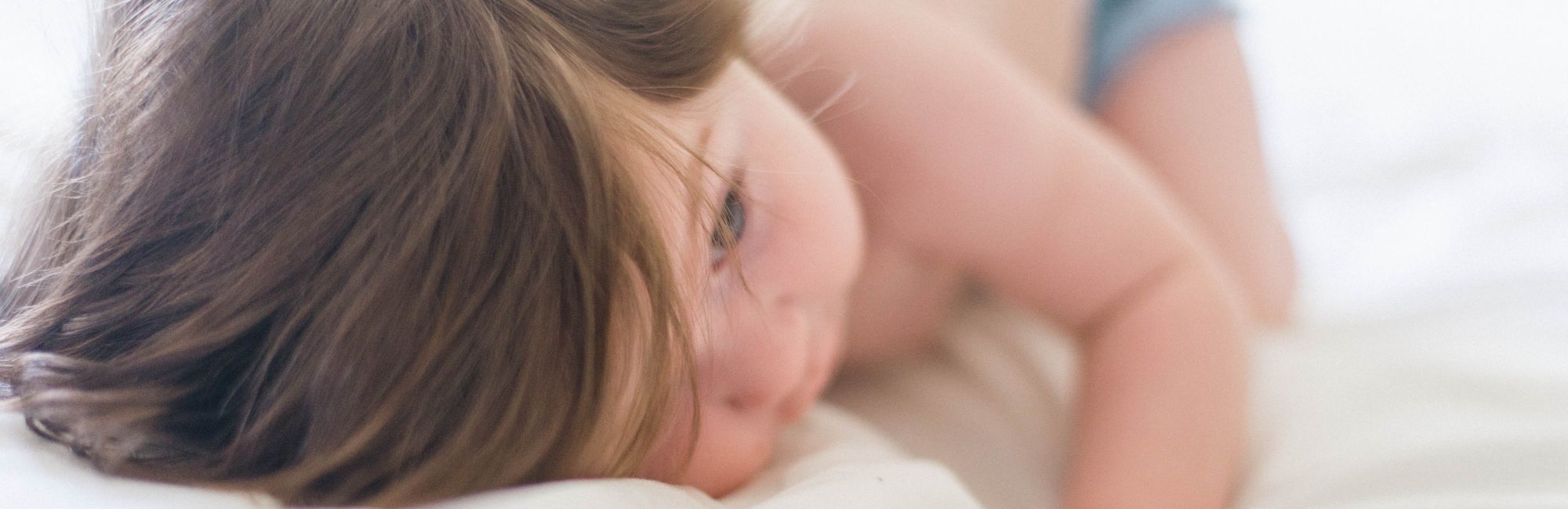green eyed toddler playing on bed after nap
