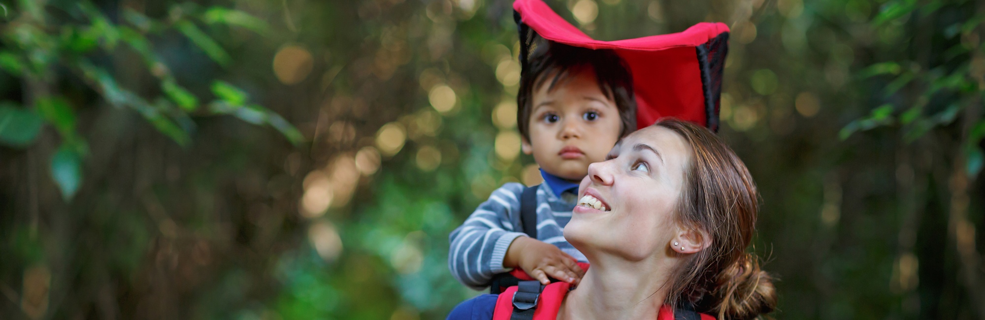 mother carries baby on her back while walking outside in nature