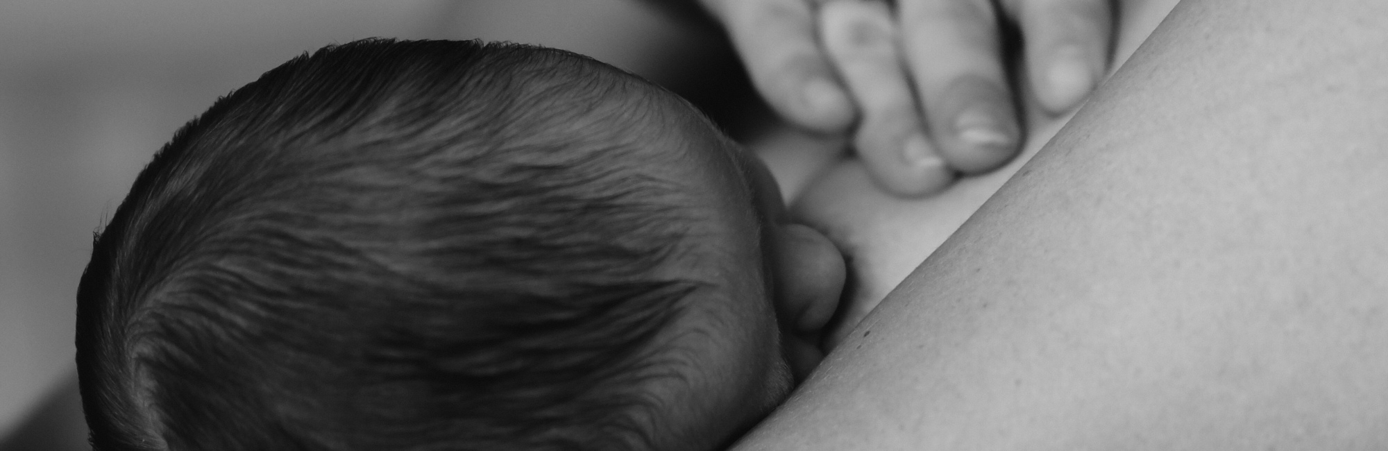 black and white photo of baby breastfeeding