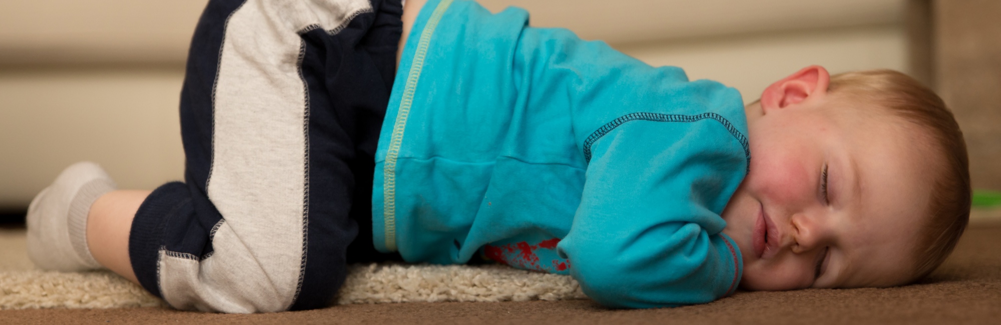tired baby asleep face down on living room rug