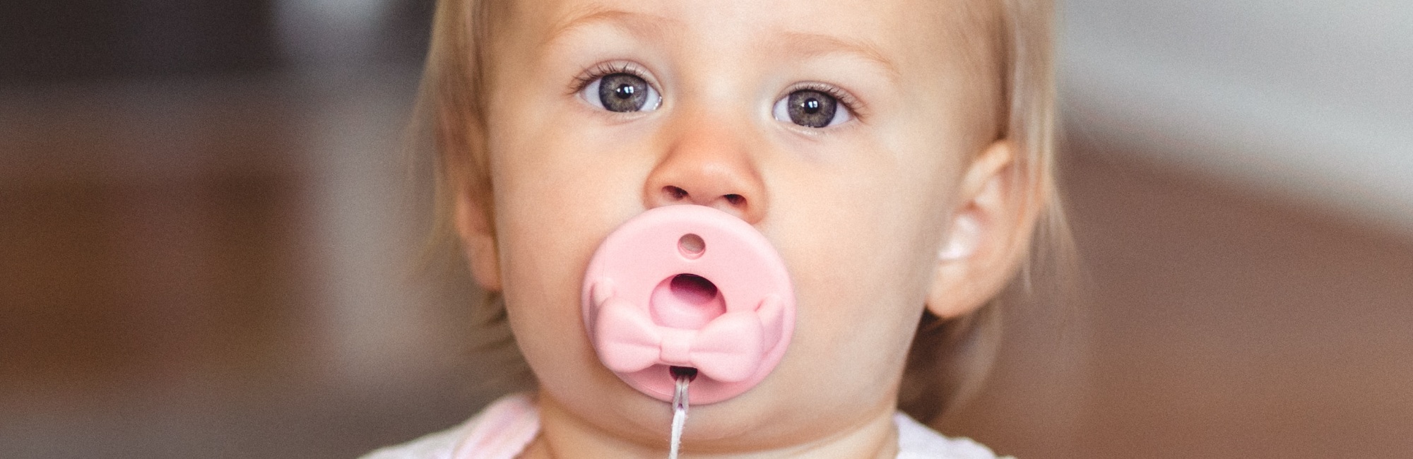 caucasian toddler using a pink dummy