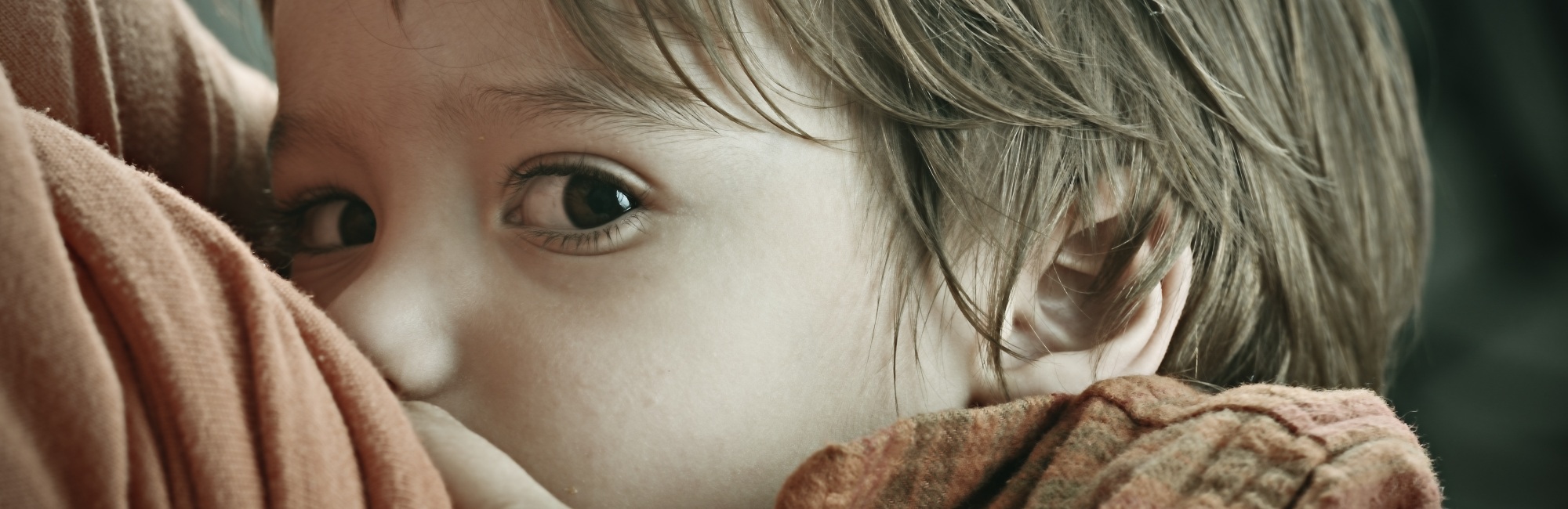 breastfeeding child with brown eyes looks at camera