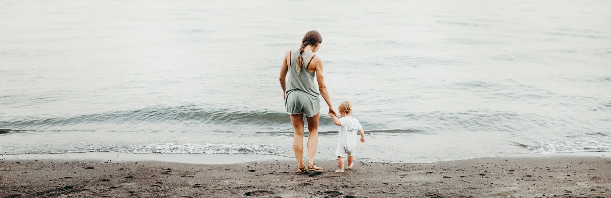 mother and toddler play by the water's edge at the sea